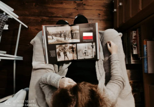 dziewczyna , siedzi, przegląda czarno-biały album z fotografiami stolicy,