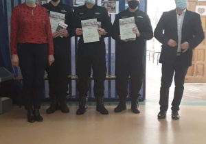Trzech uczniów klas mundurowych stoi , trzymając w ręku dyplomy za udział w konkursie.Towarzyszą im nauczyciele historii.