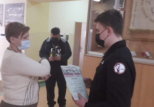 Uczeń z klasy mundurowej odbiera dyplom z rąk dyrektor szkoły.