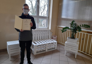 Uczeń stoi z dyplomem.
