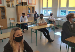 Uczniowie w ławkach w oczekiwaniu na rozpoczęcie matur.