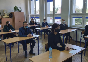 Uczniowie w ławkach w oczekiwaniu na rozpoczęcie matur.