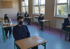 Uczniowie w ławkach w oczekiwaniu na rozpoczęcie matur.