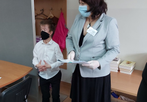 Nauczyciele i uczniowie odbierają arkusze egzaminacyjne z rąk dyrekcji.