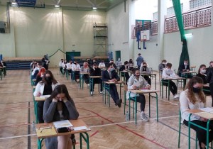 Uczniowie w ławkach w oczekiwaniu na rozpoczęcie matur.