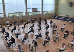 Uczniowie w ławkach w oczekiwaniu na rozpoczęcie matur.