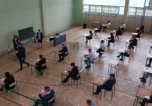 Uczniowie w ławkach w oczekiwaniu na rozpoczęcie matur.