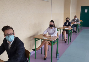 Uczniowie w ławkach w oczekiwaniu na rozpoczęcie matur.