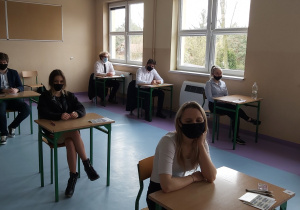 Uczniowie w ławkach w oczekiwaniu na rozpoczęcie matur.