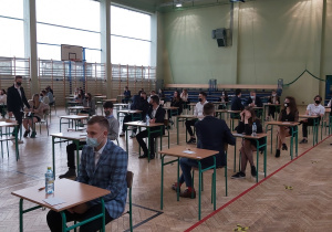 Uczniowie w ławkach w oczekiwaniu na rozpoczęcie matur.