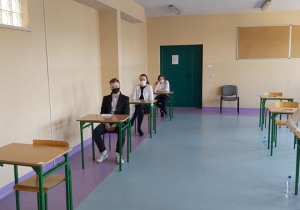 Uczniowie w ławkach w oczekiwaniu na rozpoczęcie matur.