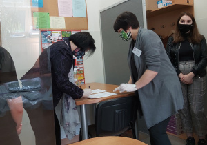 Nauczyciele i uczniowie odbierają arkusze egzaminacyjne z rąk dyrekcji.