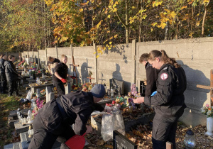 Wolontariusze Karskiego porządkują groby na cmentarzu w Bedoniu
